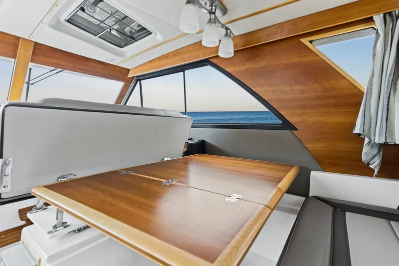Slide: The Image of Interior of 2021 Cutwater C-32 CB boat with wooden table and ocean view. - 37