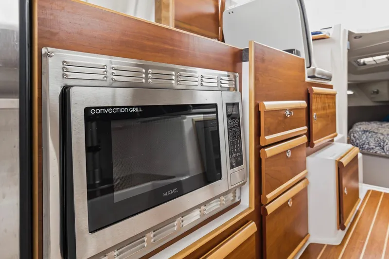 Slide: The Image of 2021 Cutwater C-32 CB interior with convection grill and wooden cabinetry. - 60