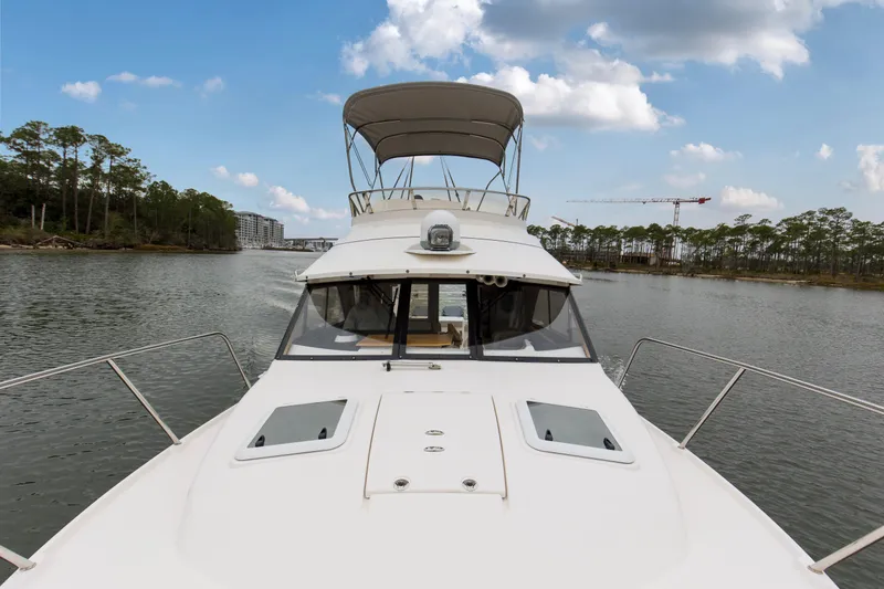 Slide: The Image of 2021 Cutwater C-32 CB boat cruising on a scenic river with trees and buildings. - 64