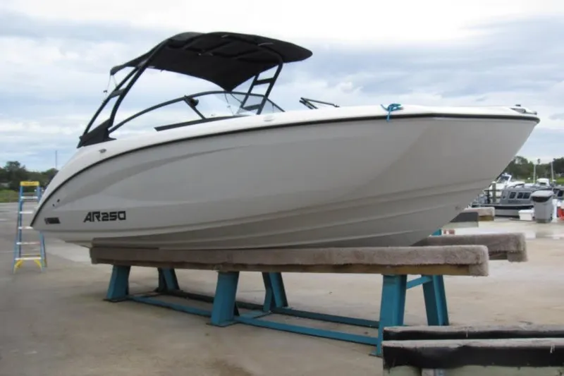 Slide: The Image of 2025 Yamaha Boats AR250 on display, elevated on stands at a marina. - 2