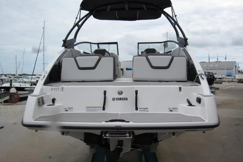 Slide: The Image of 2025 Yamaha Boats AR250, rear view at marina, showcasing sleek design and seating. - 4