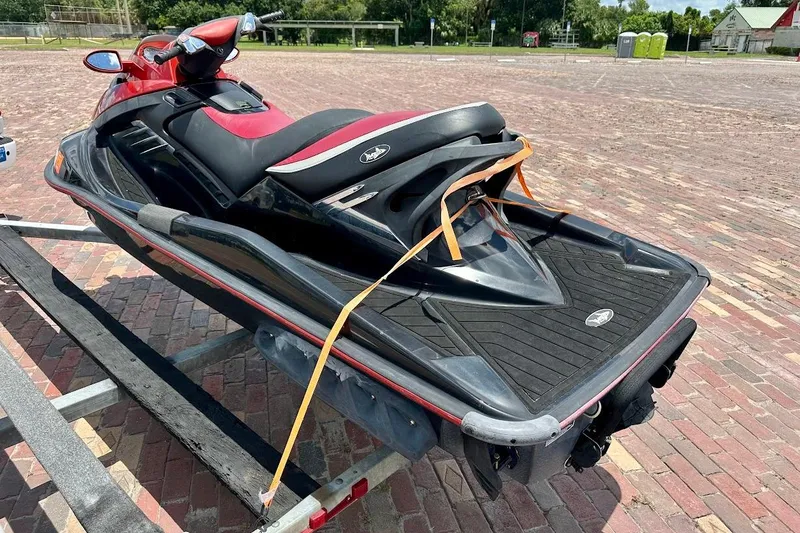 Slide: The Image of 2006 Sea-Doo RXT jet ski on trailer, red and black design, parked on brick pavement. - 3