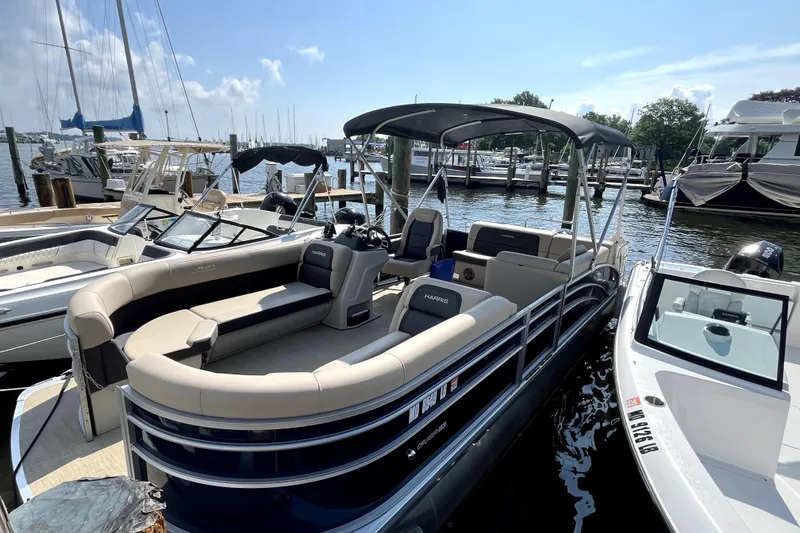 The Image of 2025 Harris HCX23 pontoon boat docked at marina under clear blue sky. - 1