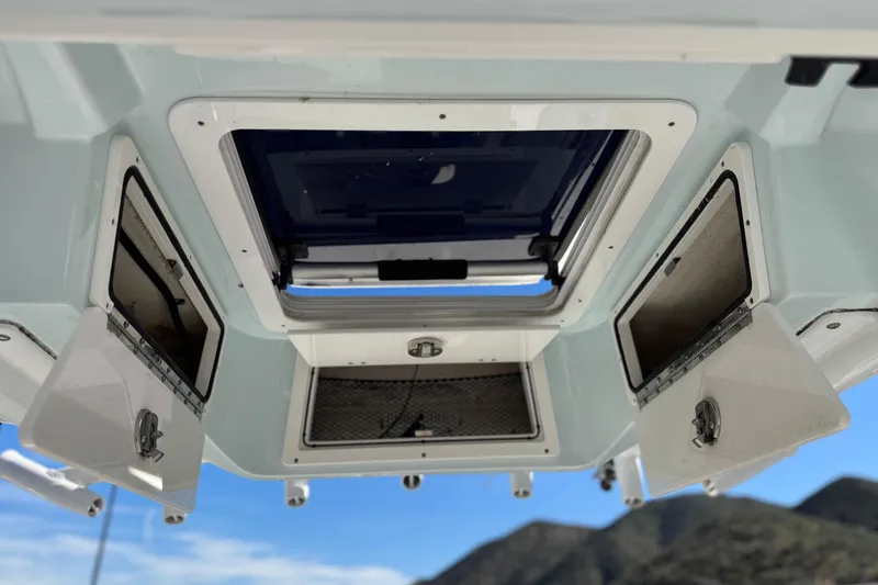 Slide: The Image of 2021 Sea Fox 268 Commander boat interior storage compartments and hatch, with mountain backdrop. - 35
