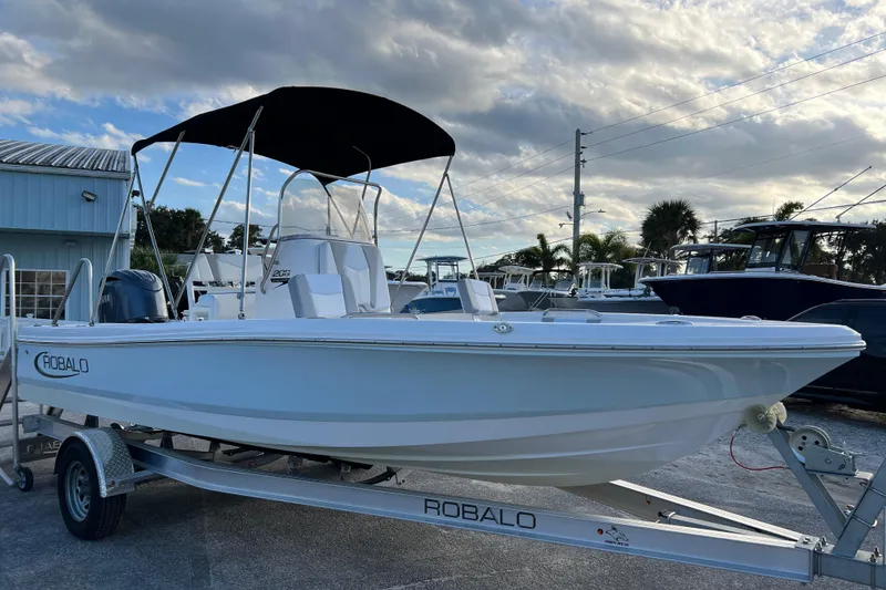 Slide: The Image of 2024 Robalo 206 Cayman boat on trailer with canopy, parked outdoors. - 2