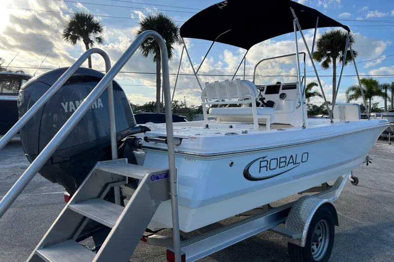 Slide: The Image of 2024 Robalo 206 Cayman boat on trailer with Yamaha engine, palm trees in background. - 8