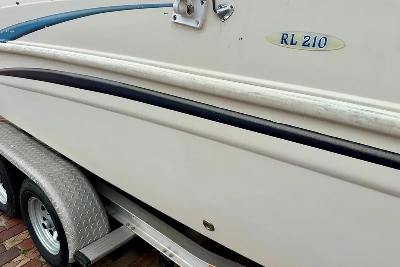 Slide: The Image of 2004 Bennington RL 210 boat on trailer, close-up view of side and logo. - 13