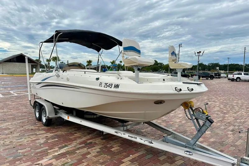 Slide: The Image of 2004 Bennington RL 210 boat on trailer in parking lot, cloudy sky background. - 2