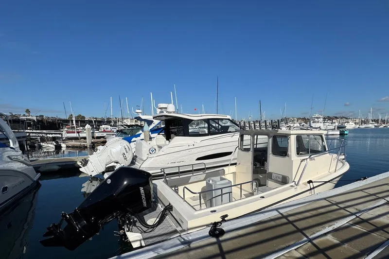 Slide: The Image of 2023 Defiance Admiral 220 EX boat docked in a marina under clear blue skies. - 12