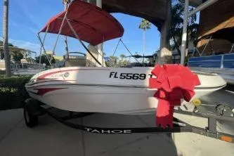 The Image of 2024 Tahoe T16 boat with red canopy and trailer, parked outdoors. - 0