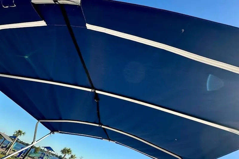 Slide: The Image of Blue canopy of 2004 Crest 2200 Family DL boat under clear sky. - 30