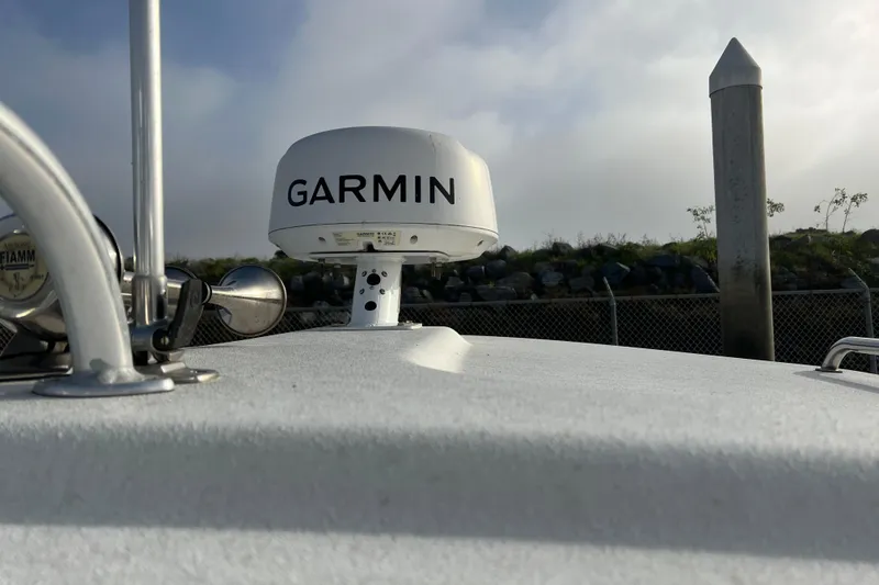 Slide: The Image of 2022 Parker 2320 Sport Cabin with Garmin radar on deck, docked near rocky shoreline. - 18