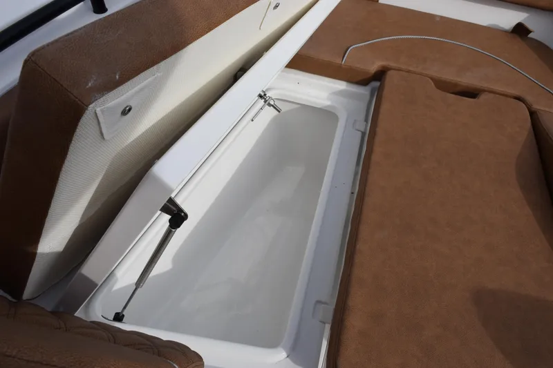 Slide: The Image of 2026 Sea Hunt Ultra 255 SE boat storage compartment with brown cushioned seating. - 19
