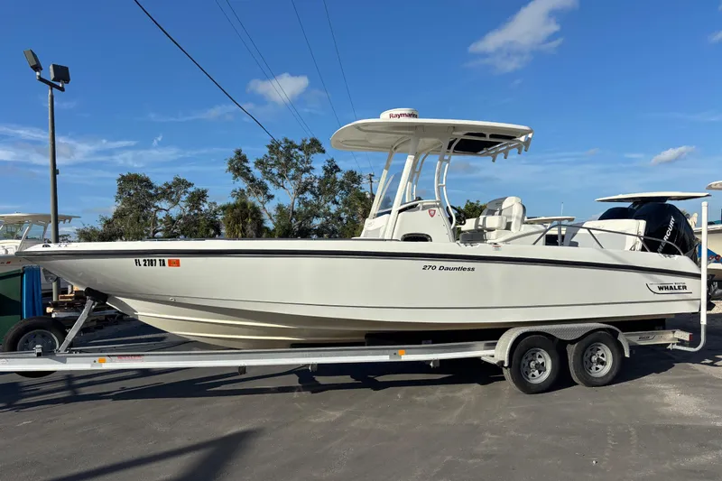 Slide: The Image of 2015 Boston Whaler 270 Dauntless boat on trailer under clear blue sky. - 0