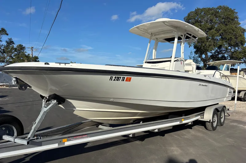 Slide: The Image of 2015 Boston Whaler 270 Dauntless boat on trailer, parked outdoors under clear sky. - 5