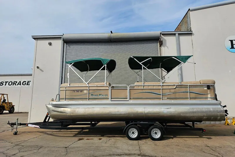 Slide: The Image of 2004 Parti Kraft Admiral 240 RE pontoon boat on trailer, parked outside storage facility. - 13