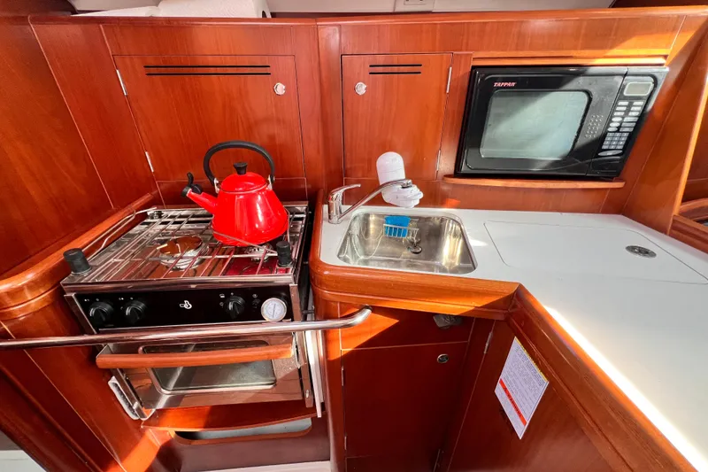 Slide: The Image of Galley kitchen in 2005 Beneteau 343 sailboat with stove, sink, and microwave. - 16