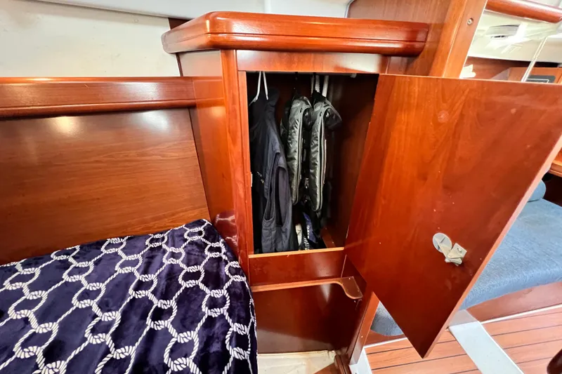 Slide: The Image of Wooden closet interior on 2005 Beneteau 343 sailboat, with hanging jackets and nautical bedding. - 32