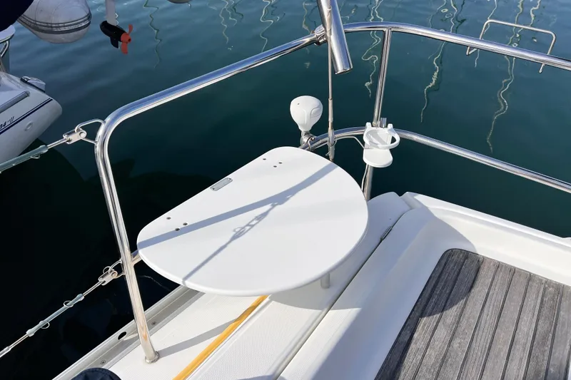 Slide: The Image of 2005 Beneteau 343 yacht stern with white table and railing, docked on calm water. - 47