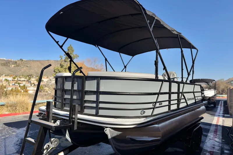 Slide: The Image of 2026 Berkshire 22UL CTS pontoon boat with canopy, parked outdoors under clear blue sky. - 3