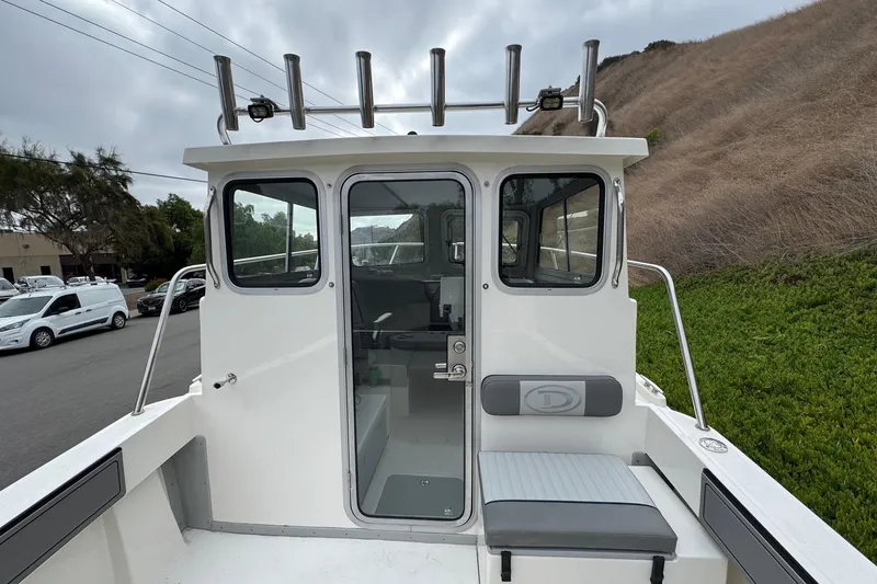 Slide: The Image of 2026 Defiance Admiral 220 EX boat with cabin and seating, docked outdoors. - 26