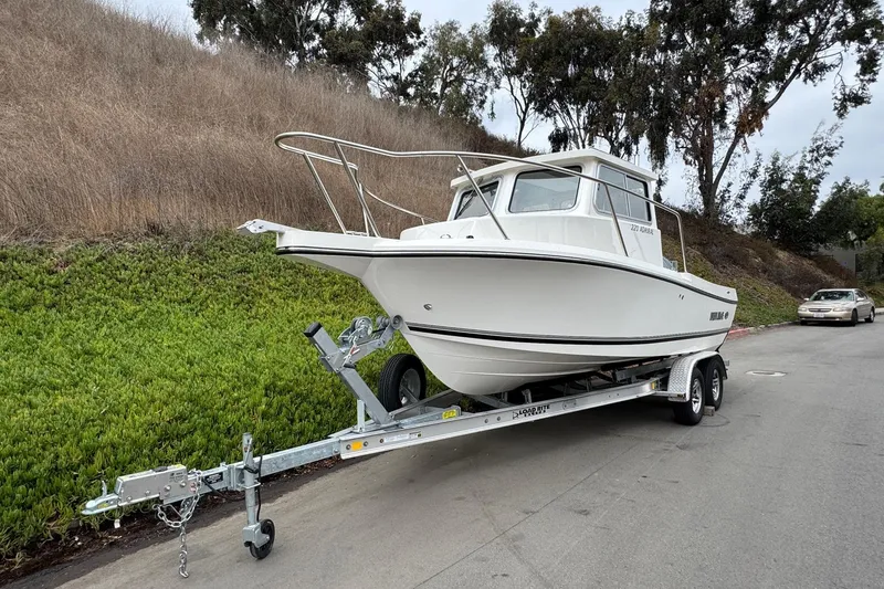Slide: The Image of 2026 Defiance Admiral 220 EX boat on trailer, parked roadside with greenery background. - 3