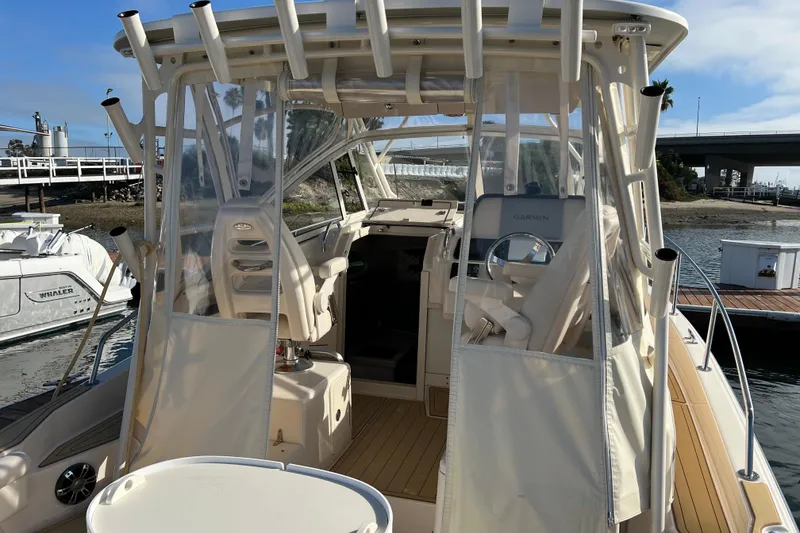 Slide: The Image of 2021 Grady-White Marlin 300 boat docked, featuring a covered helm and modern navigation equipment. - 6