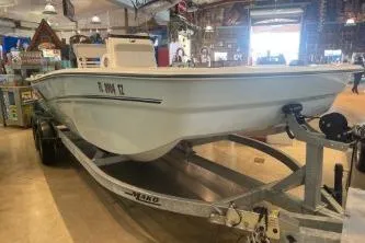 Slide: The Image of 2025 Mako Pro Skiff 19 CC boat displayed indoors on a trailer. - 74