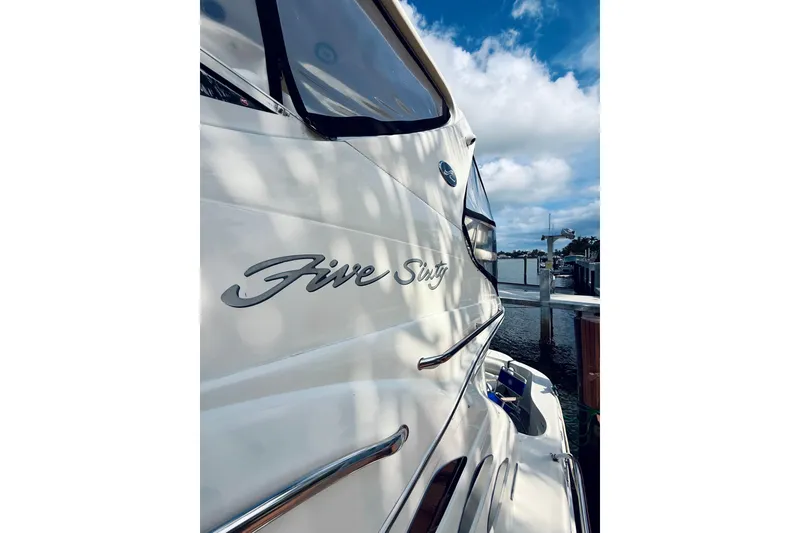 Slide: The Image of 2003 Sea Ray 560 Sedan Bridge yacht docked, featuring sleek design and "Five Sixty" name. - 2