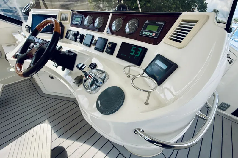 Slide: The Image of 2003 Sea Ray 560 Sedan Bridge helm with gauges, controls, and wooden steering wheel. - 27