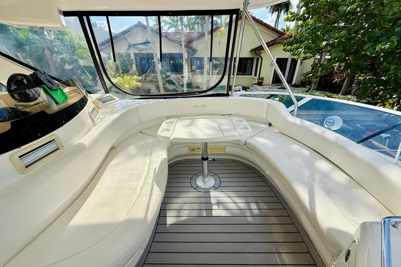 Slide: The Image of 2003 Sea Ray 560 Sedan Bridge interior with curved seating and table, surrounded by windows. - 38