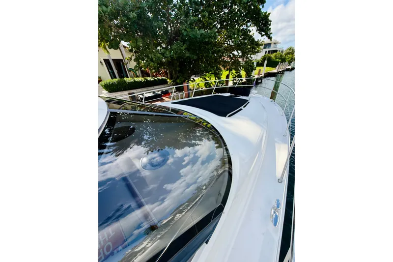 Slide: The Image of 2003 Sea Ray 560 Sedan Bridge yacht docked near lush greenery and waterfront homes. - 4