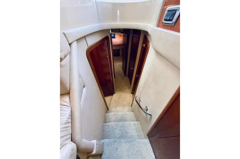 Slide: The Image of Interior staircase of 2003 Sea Ray 560 Sedan Bridge yacht, featuring plush carpeting and wooden accents. - 51