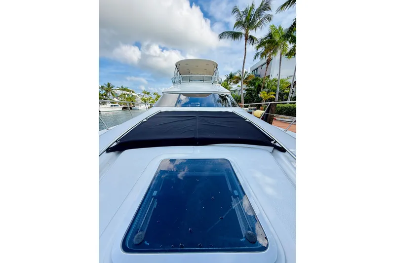 Slide: The Image of 2003 Sea Ray 560 Sedan Bridge yacht with sunroof, docked near palm trees. - 8