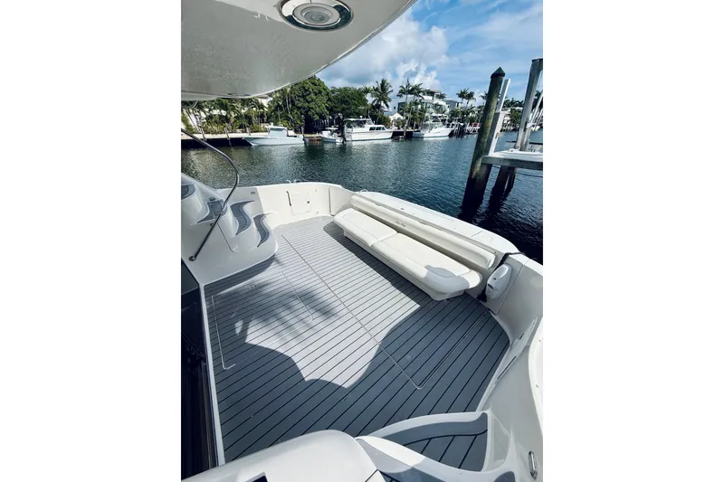 Slide: The Image of 2003 Sea Ray 560 Sedan Bridge yacht deck with seating, docked by waterfront homes. - 9