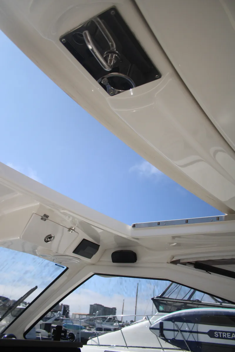 Slide: The Image of 2019 Pursuit DC 365 Dual Console boat interior with open sunroof and clear blue sky. - 11