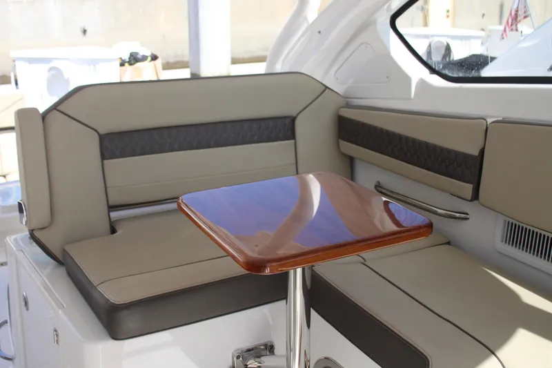 Slide: The Image of 2019 Pursuit DC 365 Dual Console interior with cushioned seating and wooden table. - 15