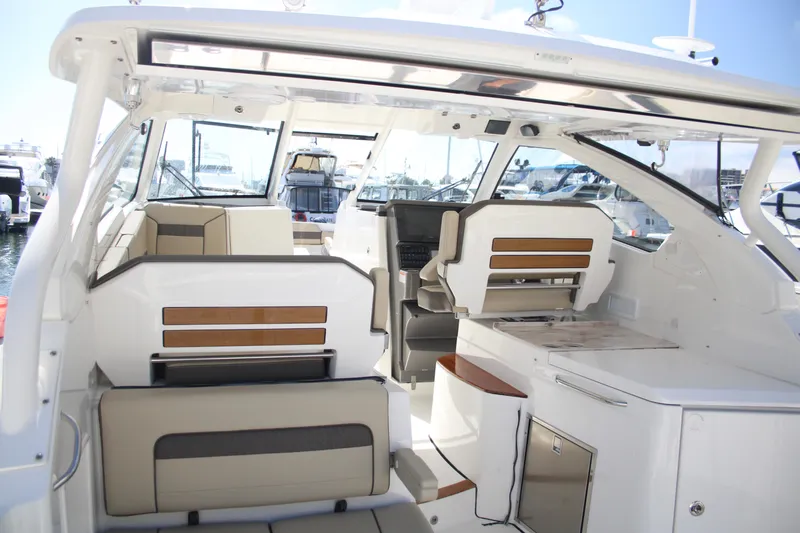 Slide: The Image of 2019 Pursuit DC 365 Dual Console boat interior with seating and helm, docked at marina. - 18