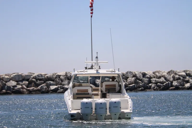Slide: The Image of 2019 Pursuit DC 365 Dual Console boat cruising near rocky shoreline. - 3