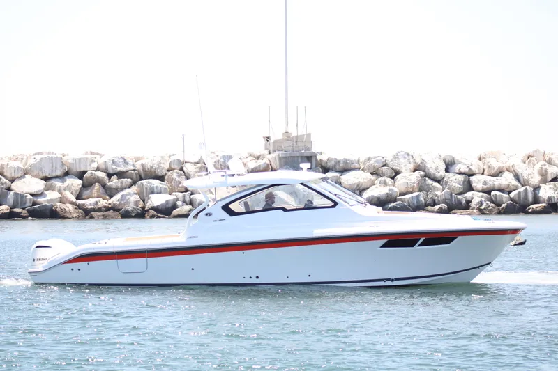 Slide: The Image of 2019 Pursuit DC 365 Dual Console boat cruising near rocky shoreline. - 5