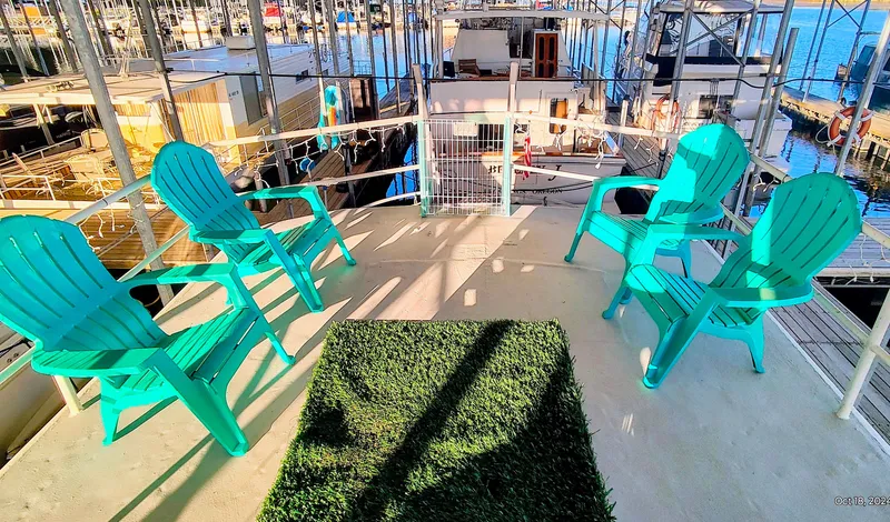 Slide: The Image of Deck of a 1964 Kelly 62' with turquoise chairs in a marina. - 15