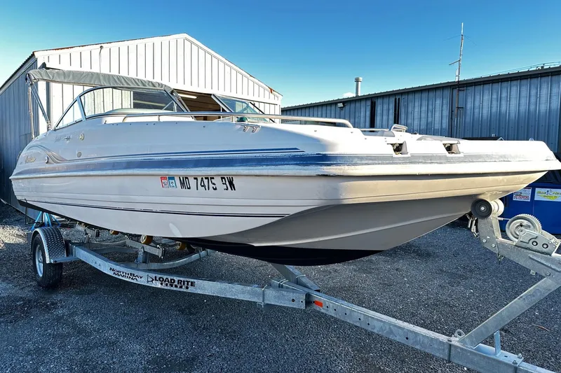 The Image of 2002 Godfrey Hurricane 237 boat on trailer, parked outside metal building. - 0