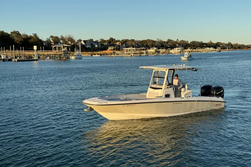 Slide: The Image of 2016 Boston Whaler 270 Dauntless boat cruising on a calm river near docks. - 13