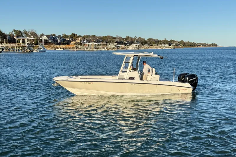 Slide: The Image of 2016 Boston Whaler 270 Dauntless boat on calm water near coastal homes. - 14