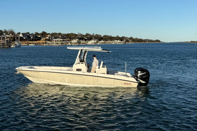 Slide: The Image of 2016 Boston Whaler 270 Dauntless boat cruising on calm waters near a coastal town. - 15