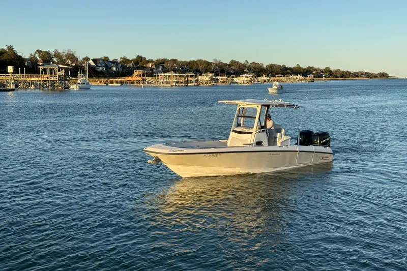 Slide: The Image of 2016 Boston Whaler 270 Dauntless boat cruising on a calm waterway near a coastal town. - 6