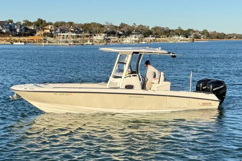Slide: The Image of 2016 Boston Whaler 270 Dauntless boat on calm water near coastal homes. - 7