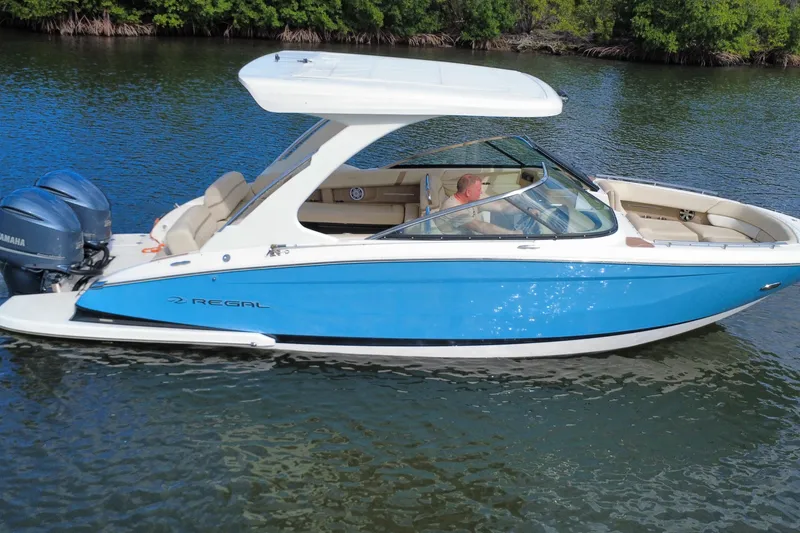 Slide: The Image of 2018 Regal 29 OBX boat cruising on a calm waterway with lush greenery. - 12