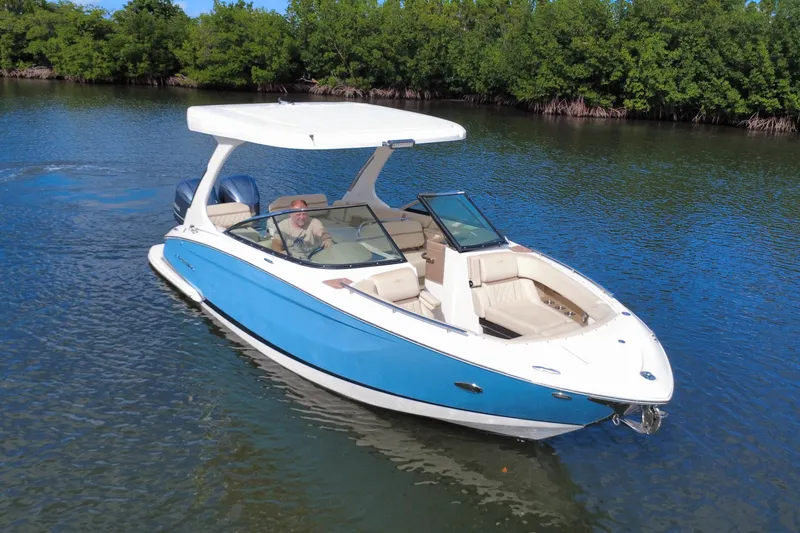 Slide: The Image of 2018 Regal 29 OBX boat cruising on a serene lake with lush greenery. - 13