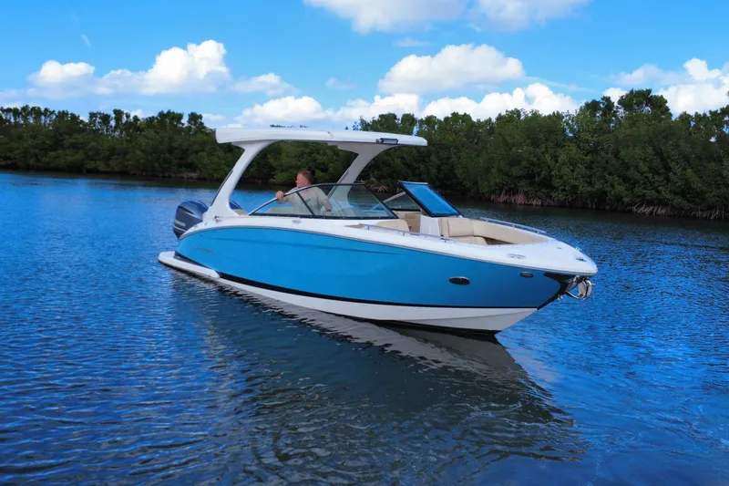 Slide: The Image of 2018 Regal 29 OBX boat cruising on a calm lake with lush greenery. - 14